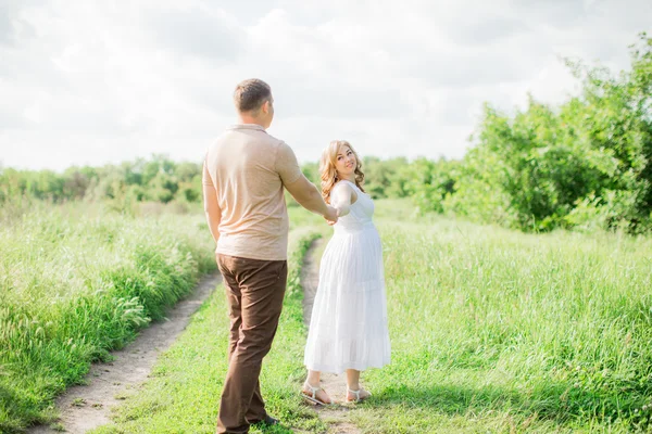 Pregnant woman with her husband in a field — Stock Photo, Image