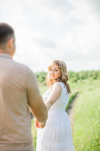 Mulher grávida com o marido em um campo — Fotografia de Stock