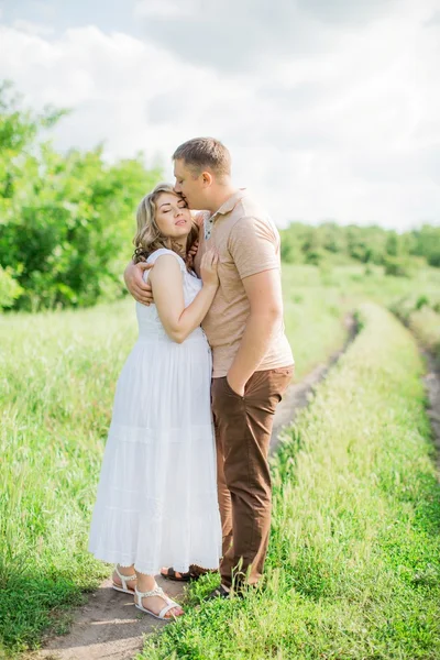 Mujer embarazada con su marido en un campo — Foto de Stock