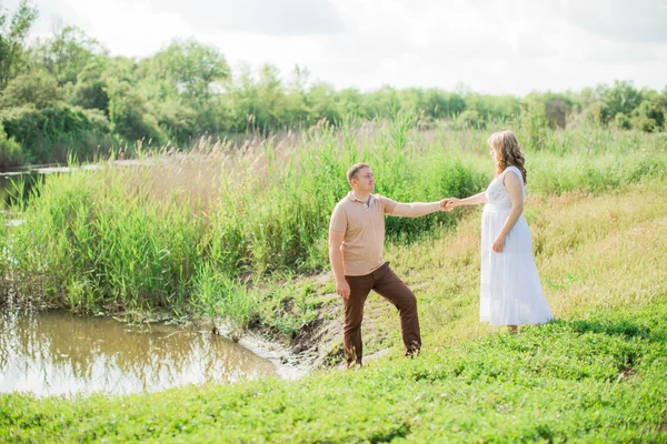 Femme enceinte avec son mari dans un champ — Photo