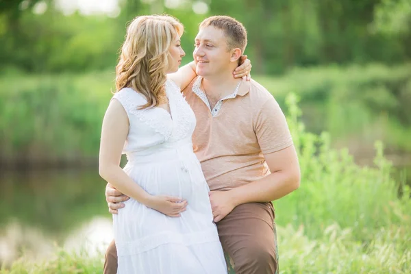 Беременная женщина с мужем в поле — стоковое фото