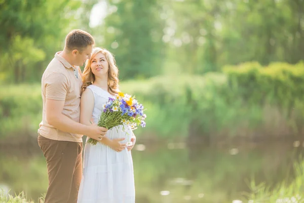 Mulher grávida com o marido em um campo — Fotografia de Stock