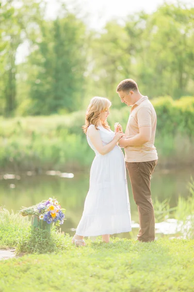 Donna incinta con il marito in un campo — Foto Stock