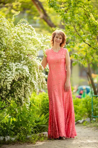 Vrouw met make-up in lange roze jurk — Stockfoto