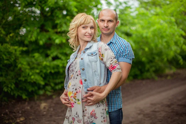 Terhes nő a férjével, kertben — Stock Fotó