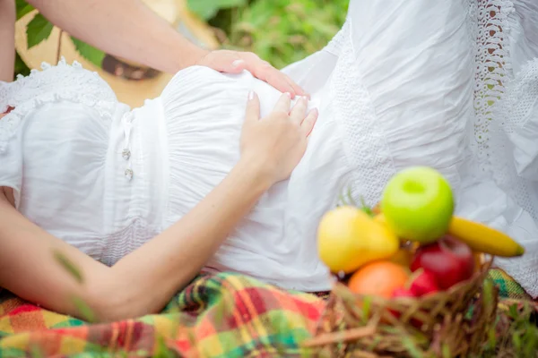 Pregnant woman with her husband in garden — Stock Photo, Image