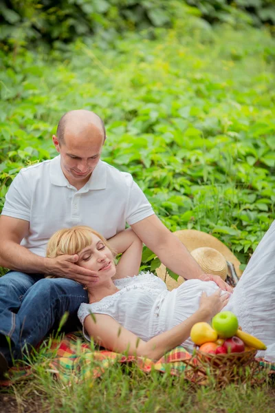 Pregnant woman with her husband in garden — Stock Photo, Image