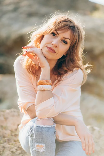 Schöne Frau auf einem Hintergrund aus Steinen — Stockfoto