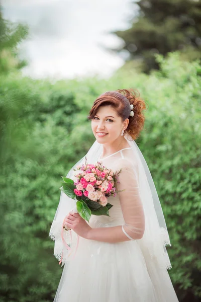 Schöne Braut im weißen Kleid mit Strauß — Stockfoto