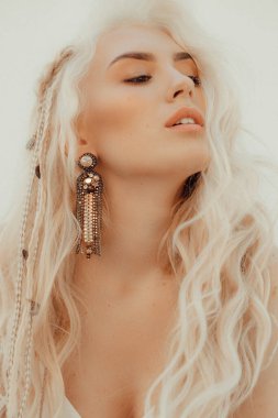 Boho tarzında beyaz elbiseli güzel bir sarışın portresi.