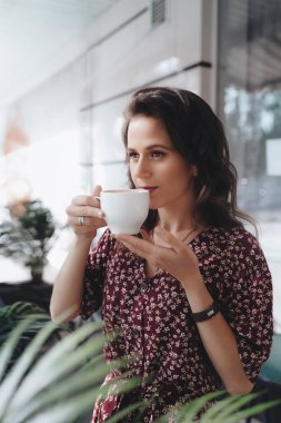 Bir yaz terasında bitkilerle dolu bir restoranda güzel bir genç kadının portresi.