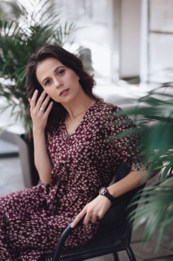 Yazın terasta bitkilerle süslenmiş şık elbiseli güzel bir kadın.