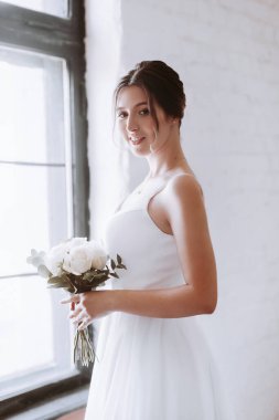 Beyaz elbiseli güzel gelin elinde bir buket çiçekle
