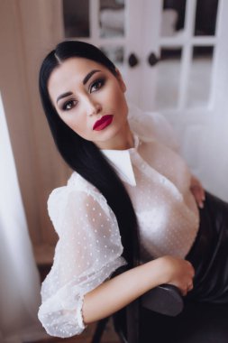 Stüdyoda poz veren beyaz bluzlu güzel bir kadın.