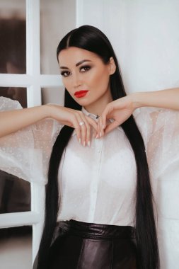 Stüdyoda poz veren beyaz bluzlu güzel bir kadın.