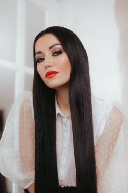 Stüdyoda poz veren beyaz bluzlu güzel bir kadın.