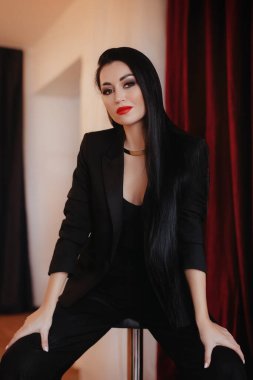 Siyah ceketli kadın stüdyoda poz veriyor.