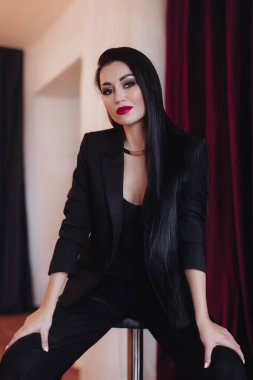 Siyah ceketli kadın stüdyoda poz veriyor.