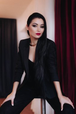 Siyah ceketli kadın stüdyoda poz veriyor.