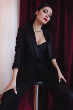 Siyah ceketli kadın stüdyoda poz veriyor.