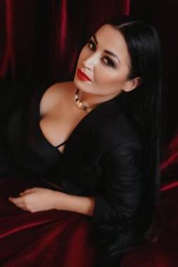 Stüdyoda poz veren siyah elbiseli güzel bir kadın.