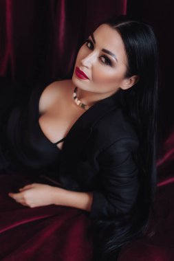 Stüdyoda poz veren siyah ceketli kırmızı dudaklı kadın.