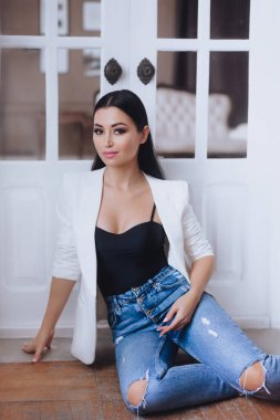 Beyaz ceketli kadın stüdyoda poz veriyor.