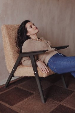 Kahverengi kazaklı ve kot pantolonlu genç kadın.