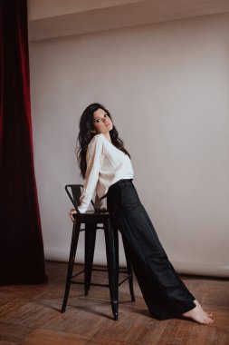 Beyaz kazaklı ve siyah pantolonlu güzel bir kadın.