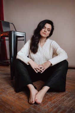  Beyaz kazaklı bir kadın yerde oturuyor.