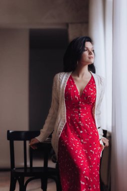 Stüdyoda poz veren kırmızı elbiseli güzel bir kadın.