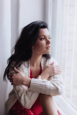 Stüdyoda poz veren kırmızı elbiseli ve hırkalı güzel bir kadın.