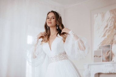 Güzel esmer gelin, açık renk makyajlı, beyaz elbiseli, zarif iç görünüşlü. 