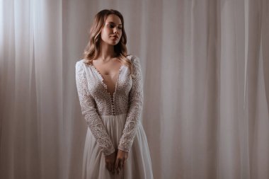 Güzel esmer gelin, açık renk makyajlı, beyaz elbiseli, zarif iç görünüşlü. 