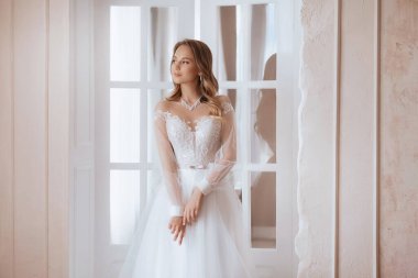 Güzel esmer gelin, açık renk makyajlı, beyaz elbiseli, zarif iç görünüşlü. 