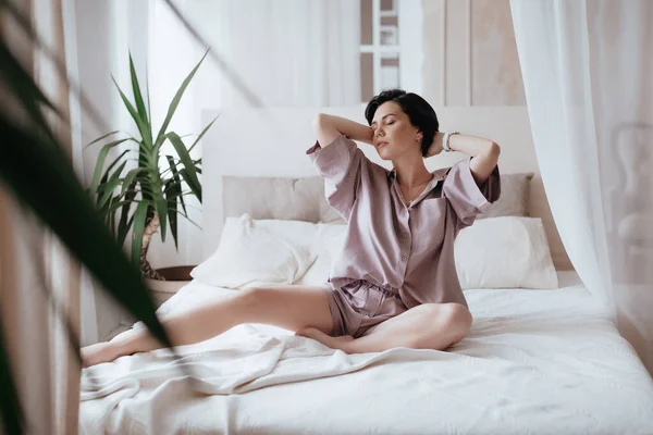 ゴージャスな美しい女の子はエレガントなパジャマでベッドにあります 自然の女性の美しさ — ストック写真