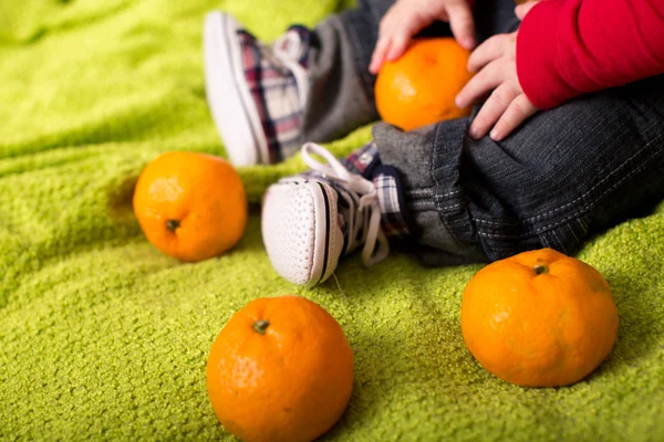 Baby with tangerines in hands — Stock Photo, Image