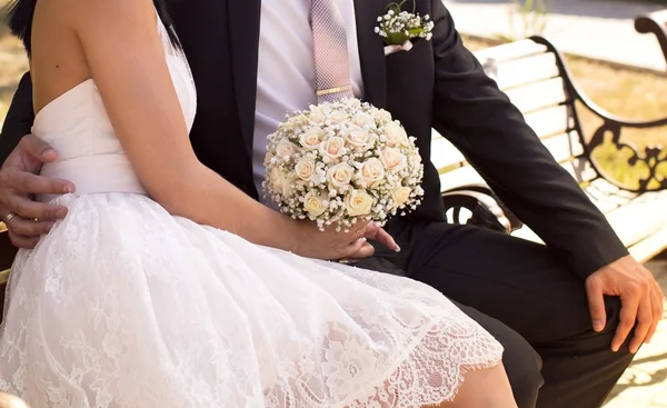 Recién casados sentados en un banco — Foto de Stock