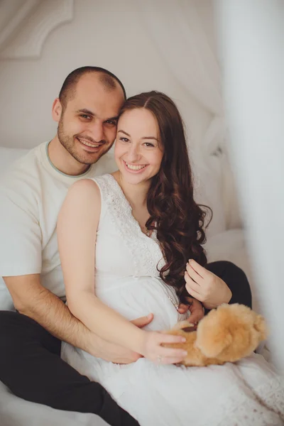Беременная женщина и ее муж в спальне — стоковое фото