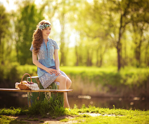 Beautiful young woman sitting near pond
