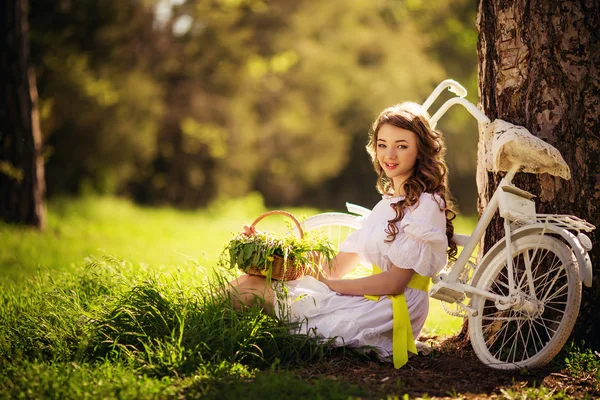 Woman with bicycle sitting under tree — Stock Photo, Image