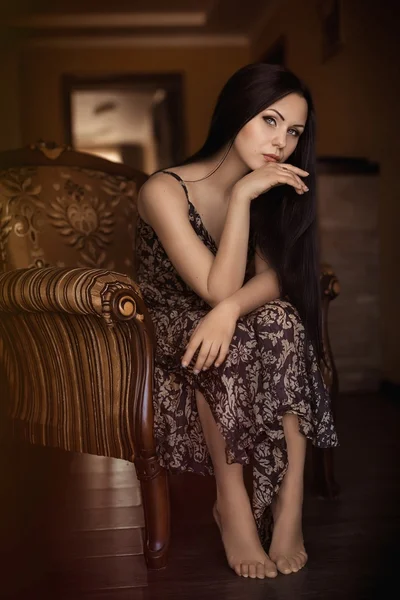 Beautiful woman sitting in an arm-chair — Stock Photo, Image