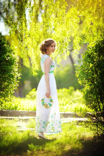 Kobieta pozowanie w wiosenny ogród z wieniec — Zdjęcie stockowe