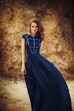 bir sahil üzerinde uzun mavi elbiseli kız