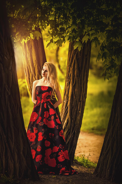 Beautiful young woman wearing a gorgeous dress in spring garden