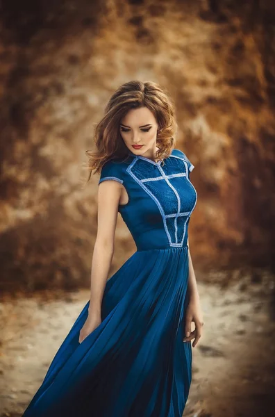 Girl in long blue dress on a seashore — Stock Photo, Image
