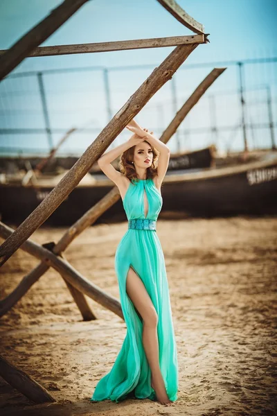 Ragazza in abito lungo blu su una riva del mare — Foto Stock