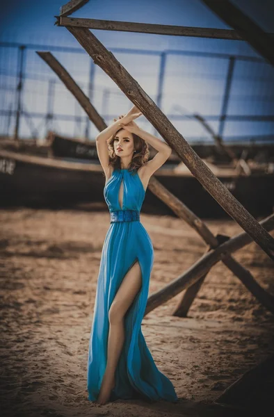 Ragazza in abito lungo blu su una riva del mare — Foto Stock
