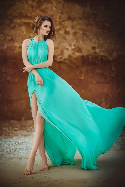 Girl in long blue dress on a seashore — Stock Photo, Image