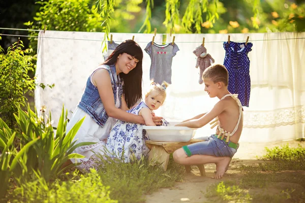 Мать с маленькими детьми с помощью стирки — стоковое фото